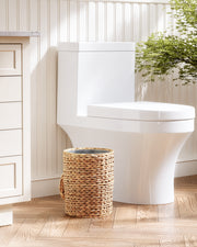 White toilet in a bathroom with a woven basket and a plant