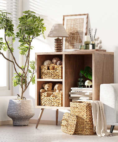 Wooden shelf with decorative items in a bright room with plants and a chair.